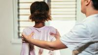A clinician examining a child’s back during a spinal assessment.