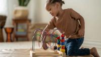 A toddler playing with a bead maze toy indoors.