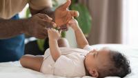 A father gently engaging his infant during a pediatric examination.