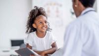 A clinician speaking with a child during a medical appointment.
