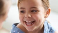 A little girl laughing while talking to a doctor