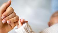 Mother's hand holding newborn baby's hand