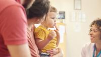 radiologist kneels down to speak with toddler and family awaiting an MRI exam.