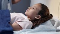 Young girl prepares to begin CT exam.