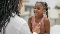 doctor holding stethoscope to smiling girl