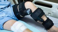 A child wearing a hinged knee brace while resting on a hospital bed,