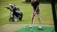 A young golfer practicing a golf swing on a driving range.