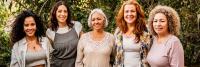 A group of five women of different ages standing outdoors.