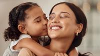 Young girl hugging and kissing her mother.