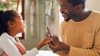 Father showing daughter how to use a glucose monitor.