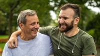 Father and son laughing together while walking outdoors.