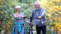Older couple walking with bike.