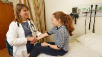 A pediatric rheumatologist exams a child