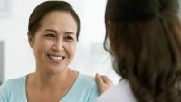 A smiling female patient listening to a doctor