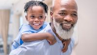 Grandfather giving piggyback to grandson at children's hospital