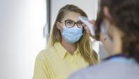 Woman having temperature checked before entering office