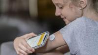 Girl checks her blood sugar level by placing her cellphone next to her pump in her arm