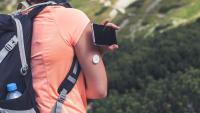 Woman hiking and checking glucose level with a remote sensor and mobile phone