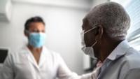 Male patient in mask speaks with doctor in mask