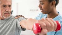 Physiotherapist working with patient as he lifts free weights