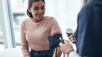 Woman has her blood pressure checked during medical exam.