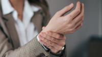 businesswoman experiencing wrist pain while working in a modern office