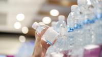 womans hand reaching for plastic water bottles