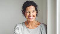 Female in grey sweater leaning against a wall