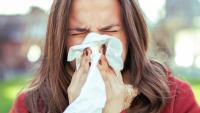 brown haired girl blowing nose grass trees allergies