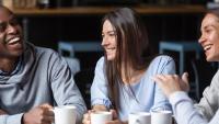 4 friends laughing and sipping coffee