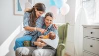 Two mothers at hospital holding their new born baby