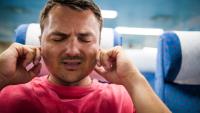 man having ear pain on airplane