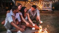 group of people roasting marshmellows by campfire