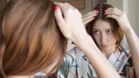 woman examining her hair in the mirror