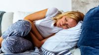 woman in stomach pain lying on a couch