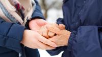 two older people holding hands in cold weather outside