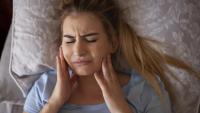 woman experiencing jaw pain in bed