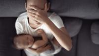 woman with headache holding baby