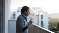 older man smoking on a balcony