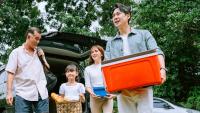 Asian family carrying cooler to picnic.