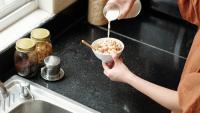woman pouring raw milk on cereal