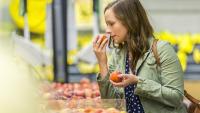 woman smelling fruit in a grocery store
