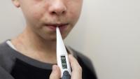 photo of a boy with a thermometer in mouth and marks on skin