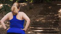 Woman holding hands on hips when observing stairs in a park that she was about to run on.