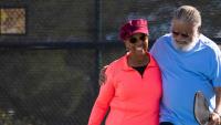 A senior African American couple playing pickle ball at the park.