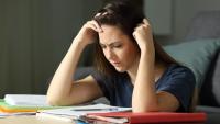 woman experiencing anguish while looking at notebooks and studying
