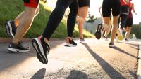 Group of women joggers run along path on sunny day.