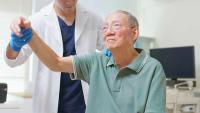 A clinician helps a patient lift their arm.
