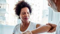 Clinician lifting a woman’s arm during exam.