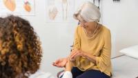 An older woman showing her wrist to a clinician.